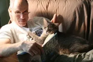 Rick reading with a cat resting on his chest