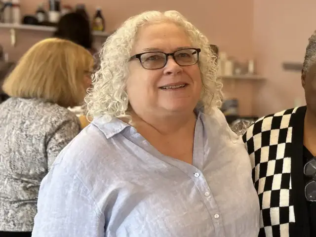 Cate Salk indoors, with curly white hair and glasses